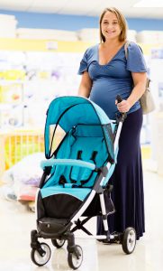 A very pregant wman smiles beautifully as she chooses a pushchair in a specialist baby shop.