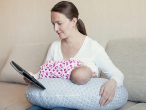 Happy mother breast feeding her newborn in room, indoor