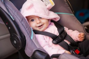 Portrait of a beautiful baby girl sitting on a car seat and smiling