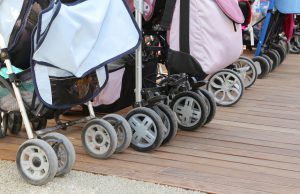 many wheels of strollers for toddlers parked on the wooden parquet floor