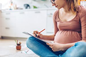 Pregnant woman at home relaxing by drawing with color pencils.